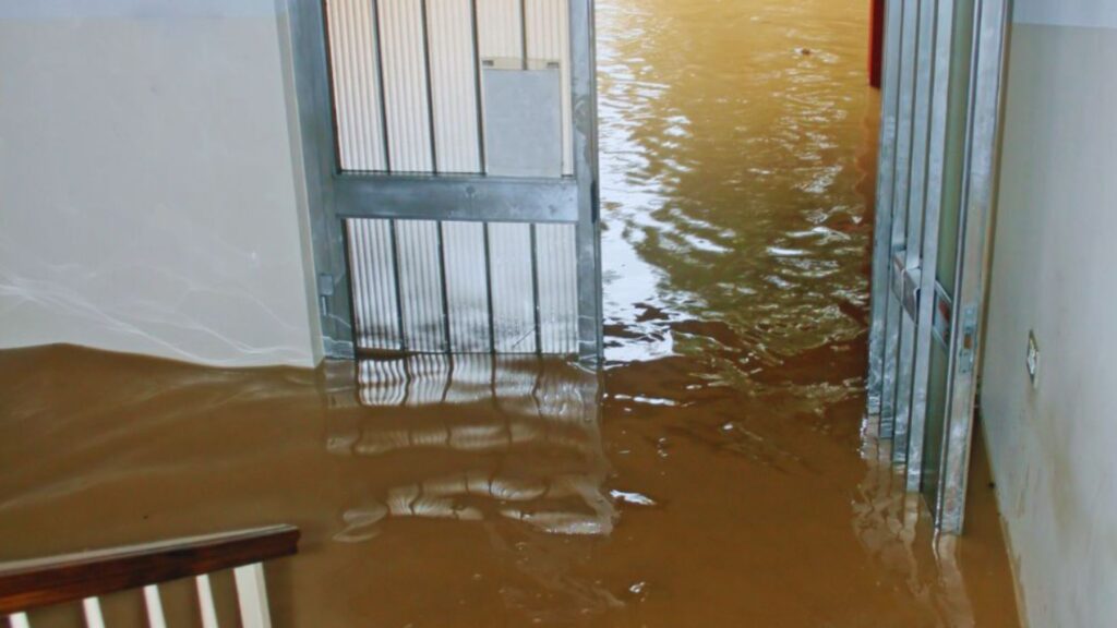 Indoor area severely flooded with murky brown water covering the floor, highlighting the need for professional water restoration services.